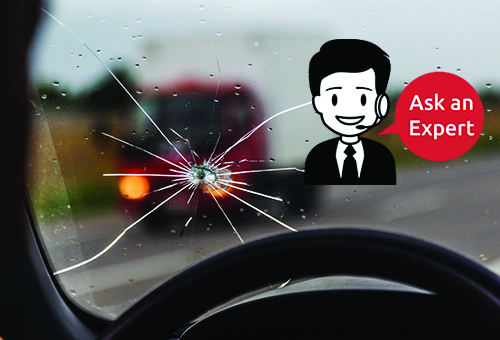 Broken windshield of a car. A web of radial splits, cracks on the triplex windshield. Broken car windshield, damaged glass with traces of oncoming stone on road or from bullet trace in car glass